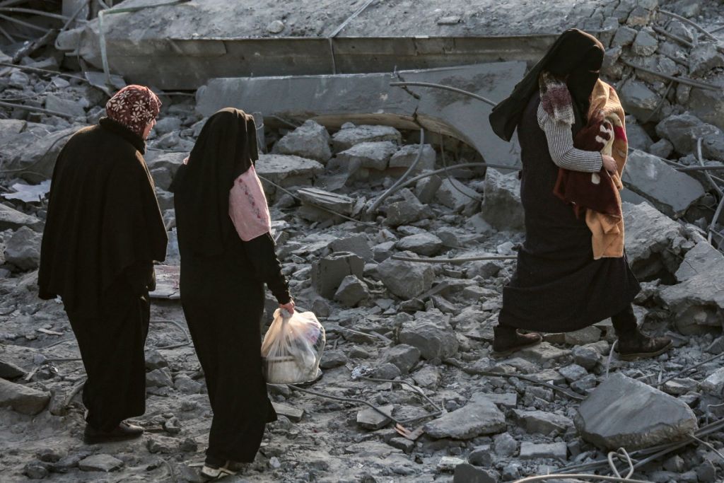 Personas en Gaza buscan objetos entre escombros de un edificio bombardeado por Israel.